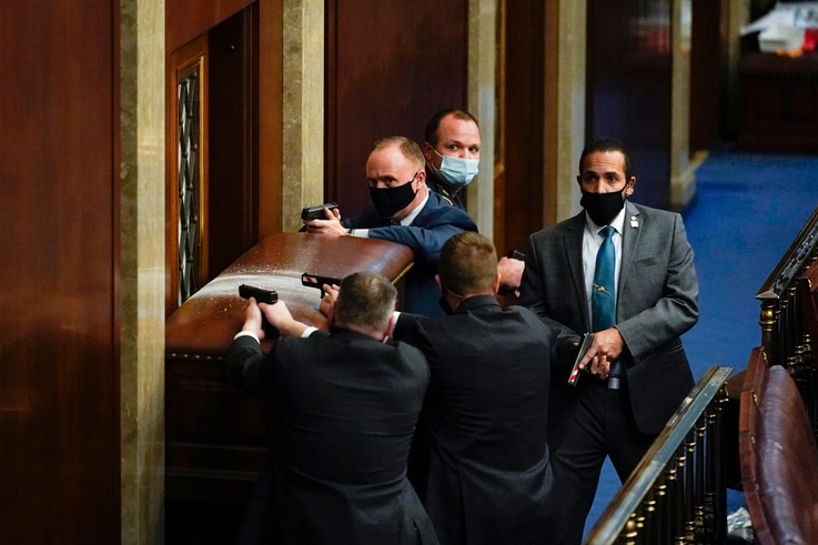 U.S. Capitol Police with guns drawn stand near a barricaded door as protesters try to break into the House Chamber at the U.S. Capitol, Jan. 6, 2021, in Washington. 
