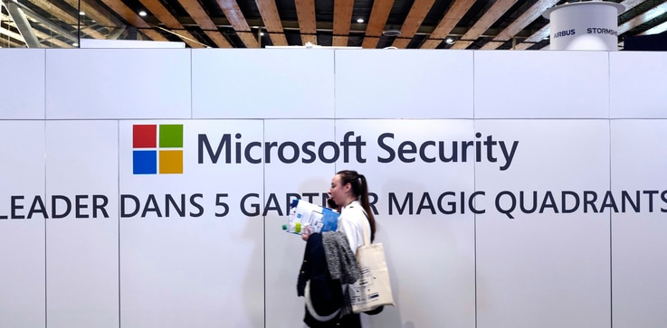 FILE - A woman walks in front of the Microsoft stand during the Cybersecurity Conference in Lille, northern France, Wednesday…