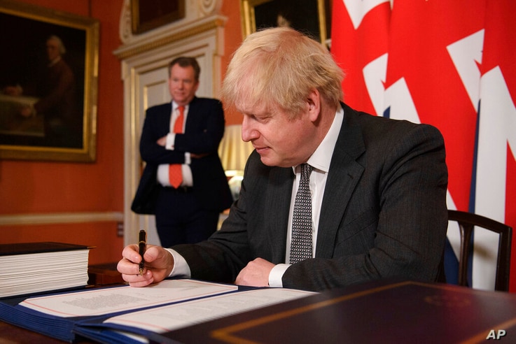 UK chief trade negotiator David Frost looks on as Britain's Prime Minister Boris Johnson signs the EU-UK Trade and Cooperation…