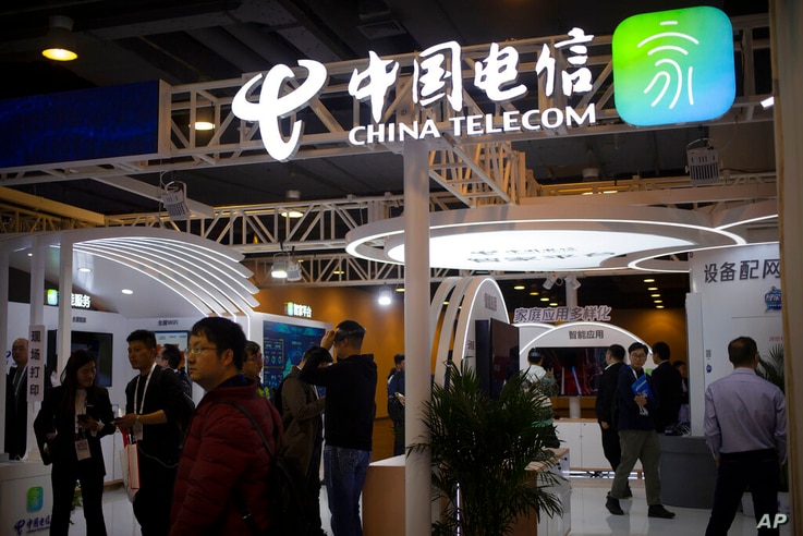 Visitors look at a display from Chinese telecommunications firm China Telecom at the PT Expo in Beijing, Thursday, Oct. 31,…