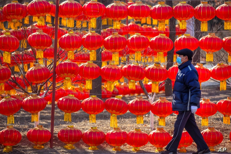 A man wearing a face mask to protect against the spread of the coronavirus walks past a display of lanterns at a public park in Beijing, Jan. 5, 2021.