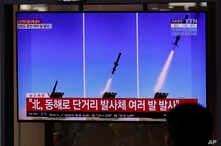 People watch a TV screen airing reports about North Korea's firing missiles with file images of missiles at the Seoul Railway…