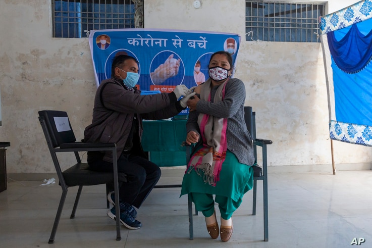 A health worker pretends to administer a shot of a COVID-19 vaccine to a volunteer during a mock vaccination drill at a school in Dharmsala, India, Jan. 11, 2021. 