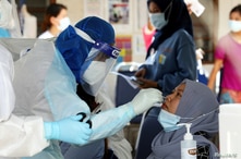 FILE - A medical worker collects a swab sample from a Top Glove worker to be tested for the COVID-19 outside a hostel under enhanced lockdown in Klang, Malaysia, Nov. 18, 2020. 