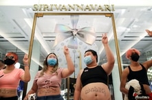 Protest leaders wearing crop tops and showing the three-finger salute, pose in front of Thailand's Princess Sirivannavari fashion boutique at Siam Paragon shopping center, as they protest against the monarchy, in Bangkok, Dec. 20, 2020.
